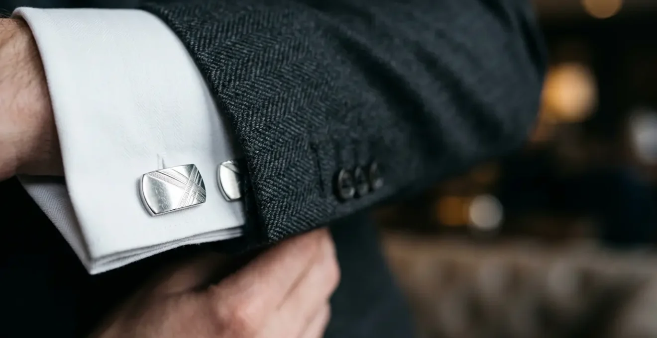 Gros plan sur des boutons de manchette élégants en argent portés avec une chemise blanche et une veste formelle