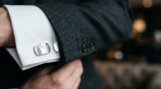 Gros plan sur des boutons de manchette élégants en argent portés avec une chemise blanche et une veste formelle