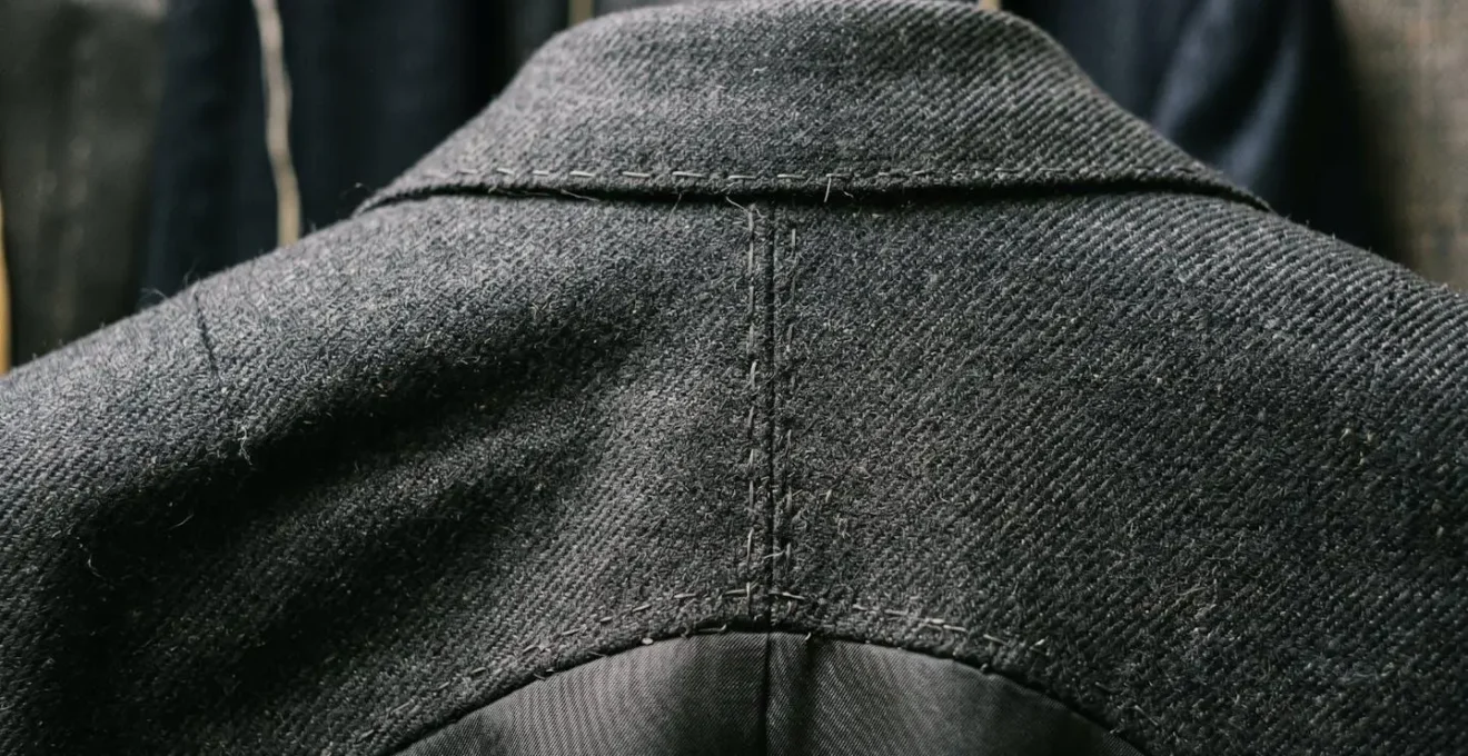 Détail macro de la construction d'un revers de costume entoilé avec texture visible du tissu et coutures artisanales