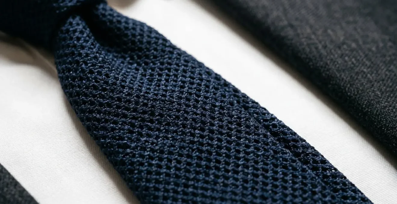 Détail d'une cravate en grenadine de soie sur une chemise blanche et costume gris