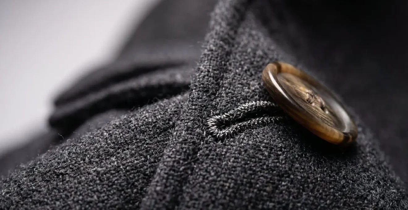 Gros plan sur le boutonnage d'une veste croisée montrant la tension du tissu et les détails de construction