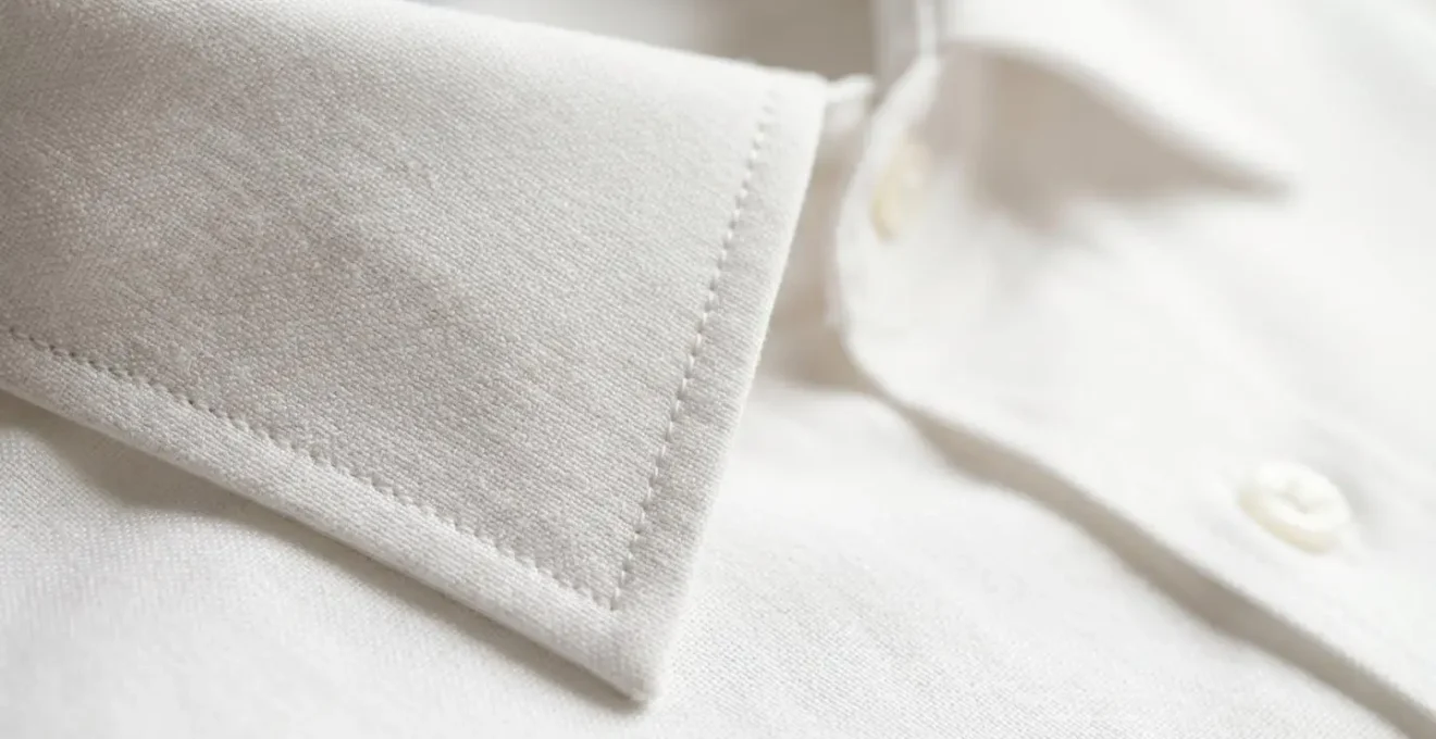 Détail macro du col d'une chemise blanche montrant la texture du tissu et la structure