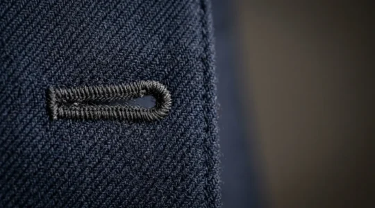 Détail macro d'un costume classique bleu marine sur mesure montrant la texture de laine de qualité et les finitions artisanales