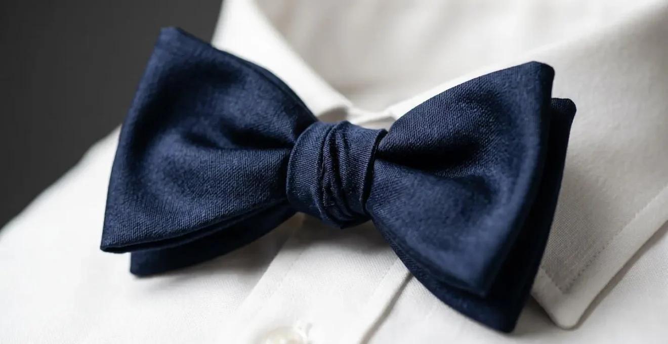 Détail macro d'un nœud papillon en soie légèrement asymétrique illustrant la sprezzatura