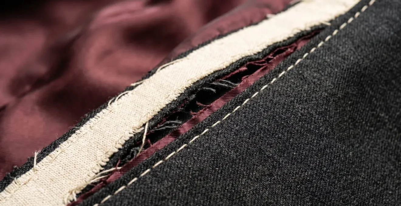 Vue en coupe d'une couture de veste de costume montrant la réserve de tissu cachée à l'intérieur