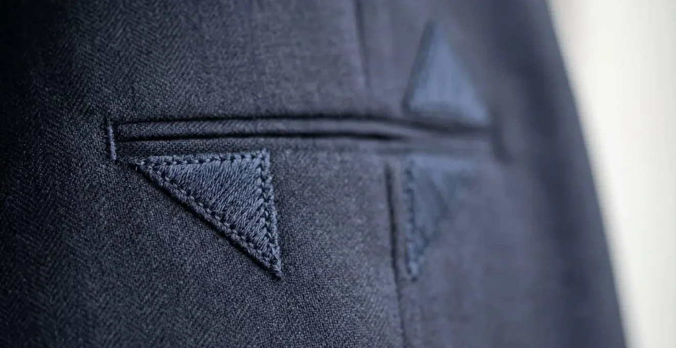 Vue détaillée des triangles de renfort parfaitement symétriques aux extrémités d'une poche passepoilée de qualité